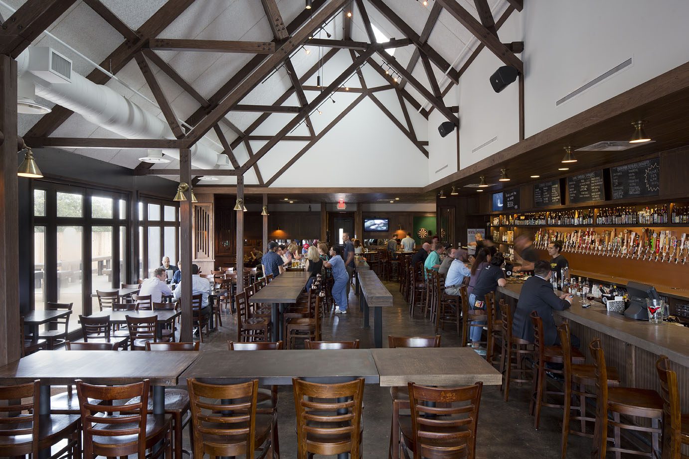 The main room by day, timber trusses above the bar and its wall of taps.
