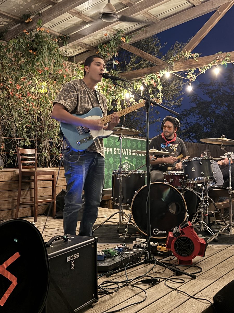 A band playing on the covered patio stage under string lights.
