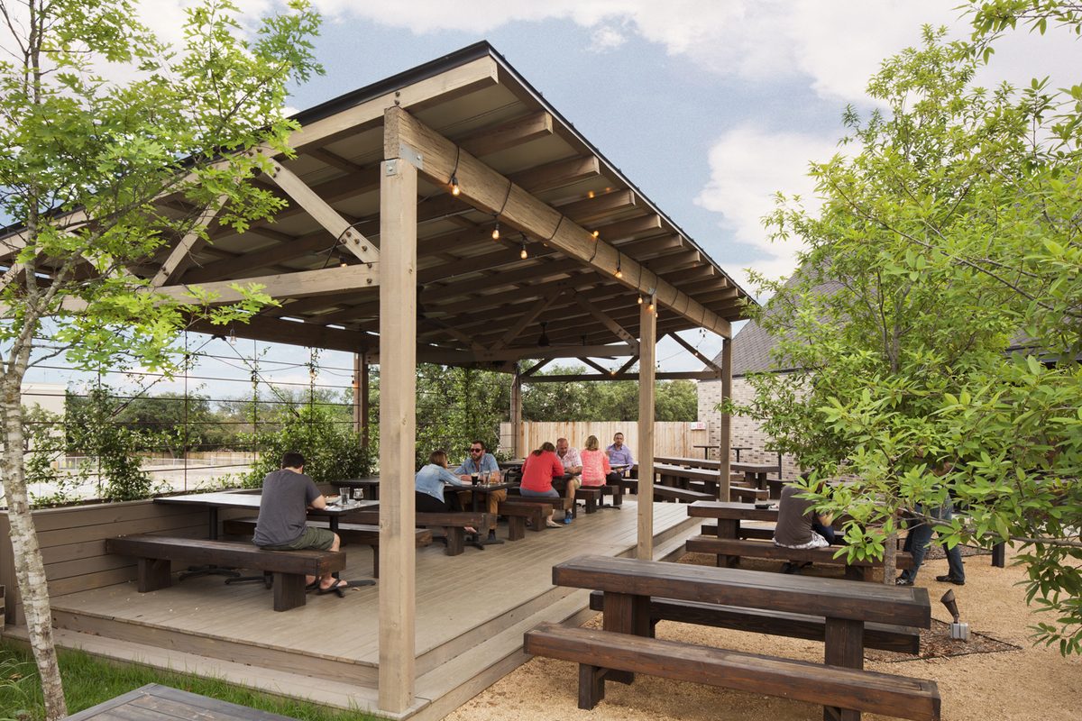 Groups seated at long picnic tables under the patio pavilion.