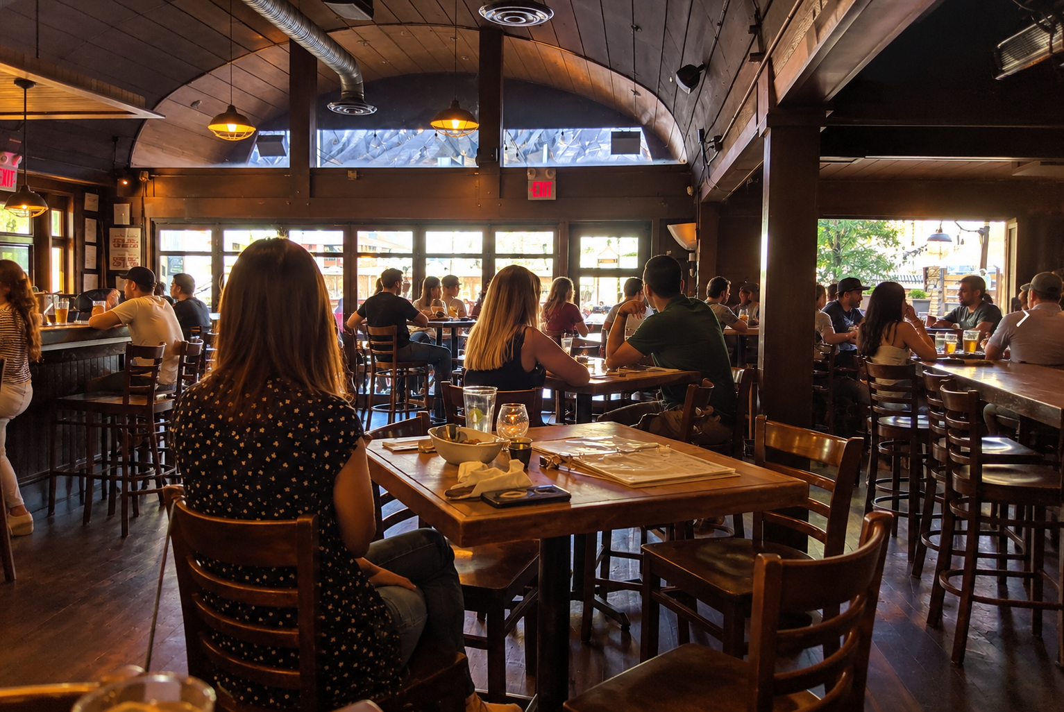 The dining room in the afternoon, tables full and the patio doors folded open.